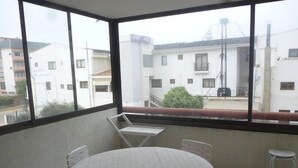 A balcony with a round table and chairs, a view of buildings, and a clear sky. - Depto Centro Algarrobo 1029 (Algarrobo)