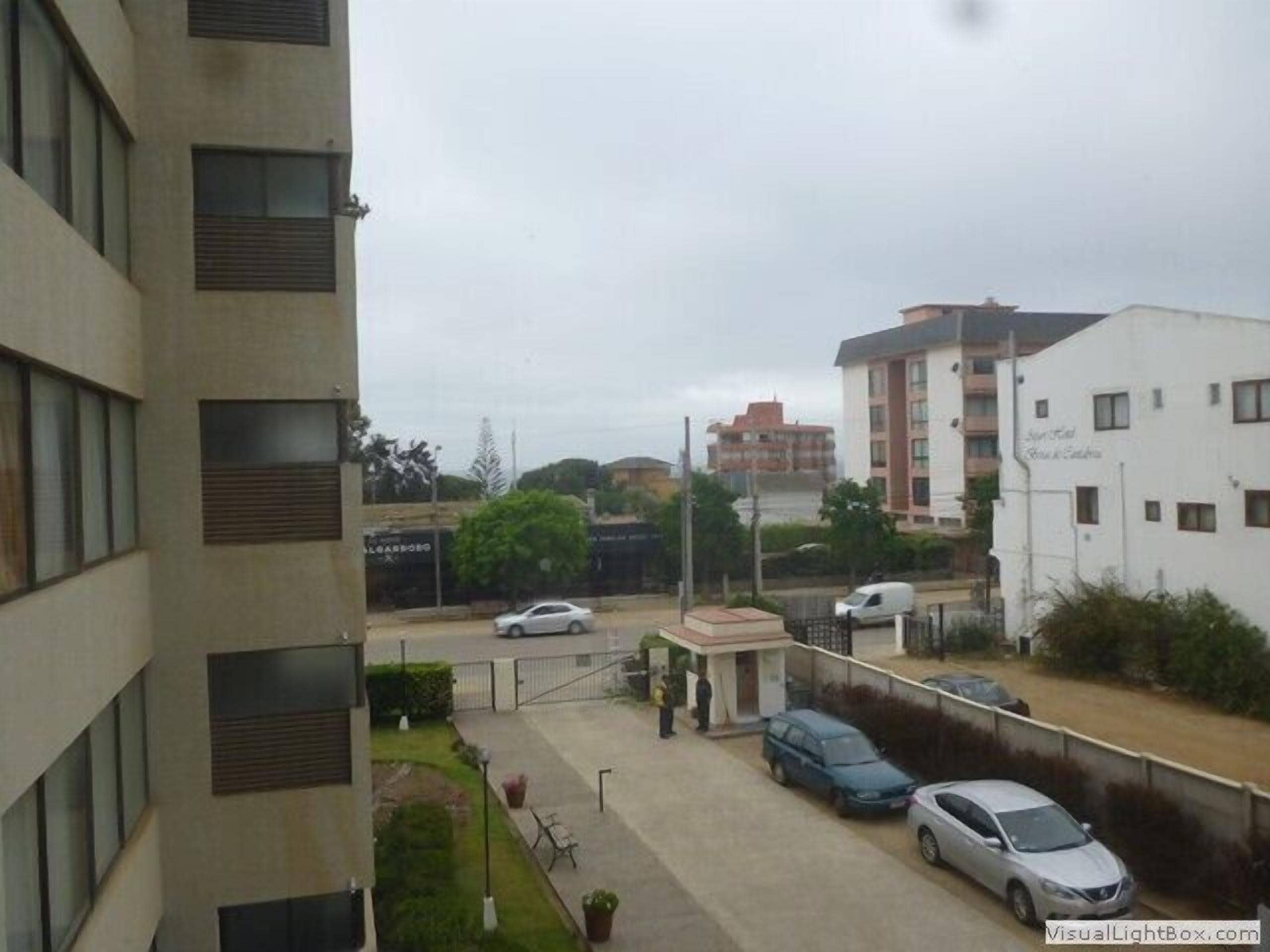A multi-story building with a parking area in front.