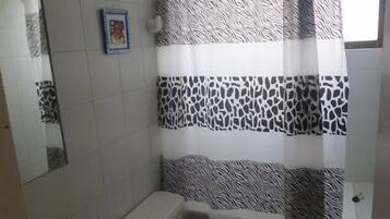 Um banheiro com cortina de chuveiro listrada em zebra, pia branca e espelho na parede.