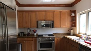 A kitchen with wooden cabinets, stainless steel appliances, and a window providing natural light. - Blue Orchid Villa (Moss Town)