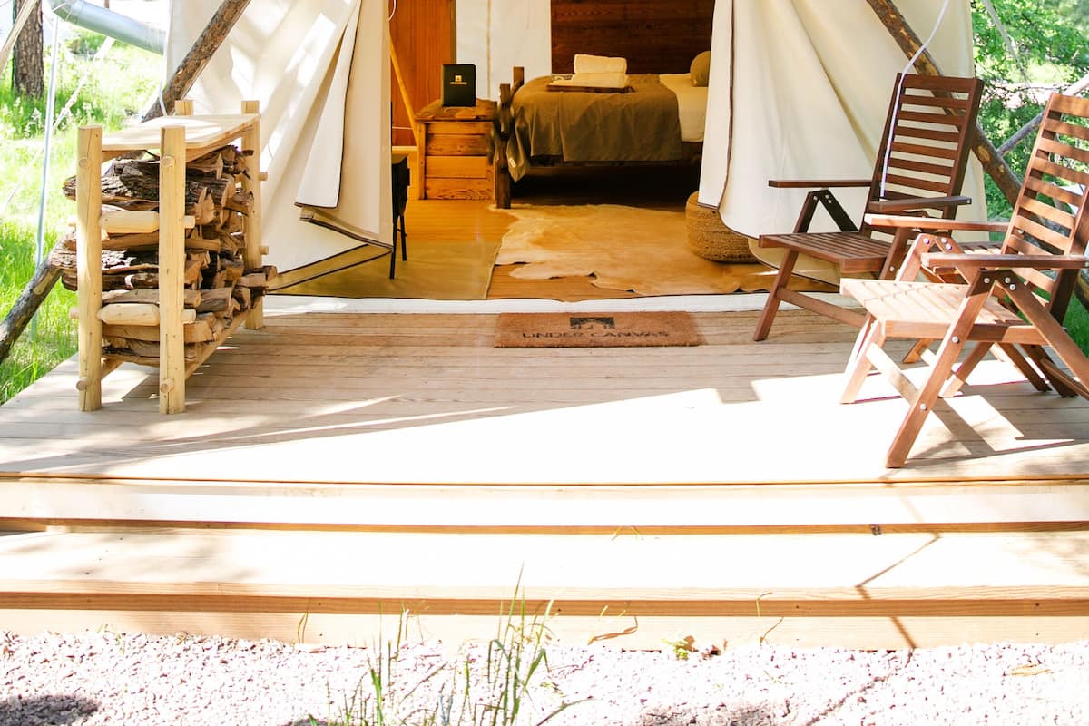 Una carpa con piso de madera, una cama y una pequeña mesa.