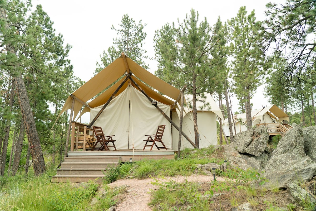 Alojamiento con carpa, terraza de madera y dos sillas.