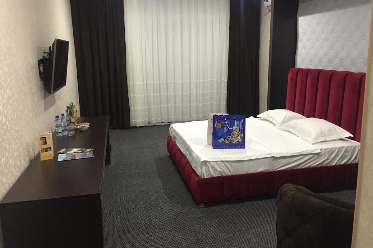 Ein Hotelzimmer mit Bett, Schreibtisch und Wandfernseher.