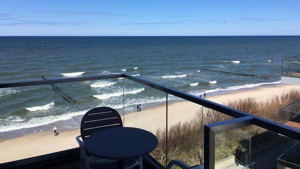 Un balcon avec vue sur l’océan, une table et des chaises.