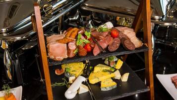 A charcuterie board with various meats, cheeses, and garnishes.