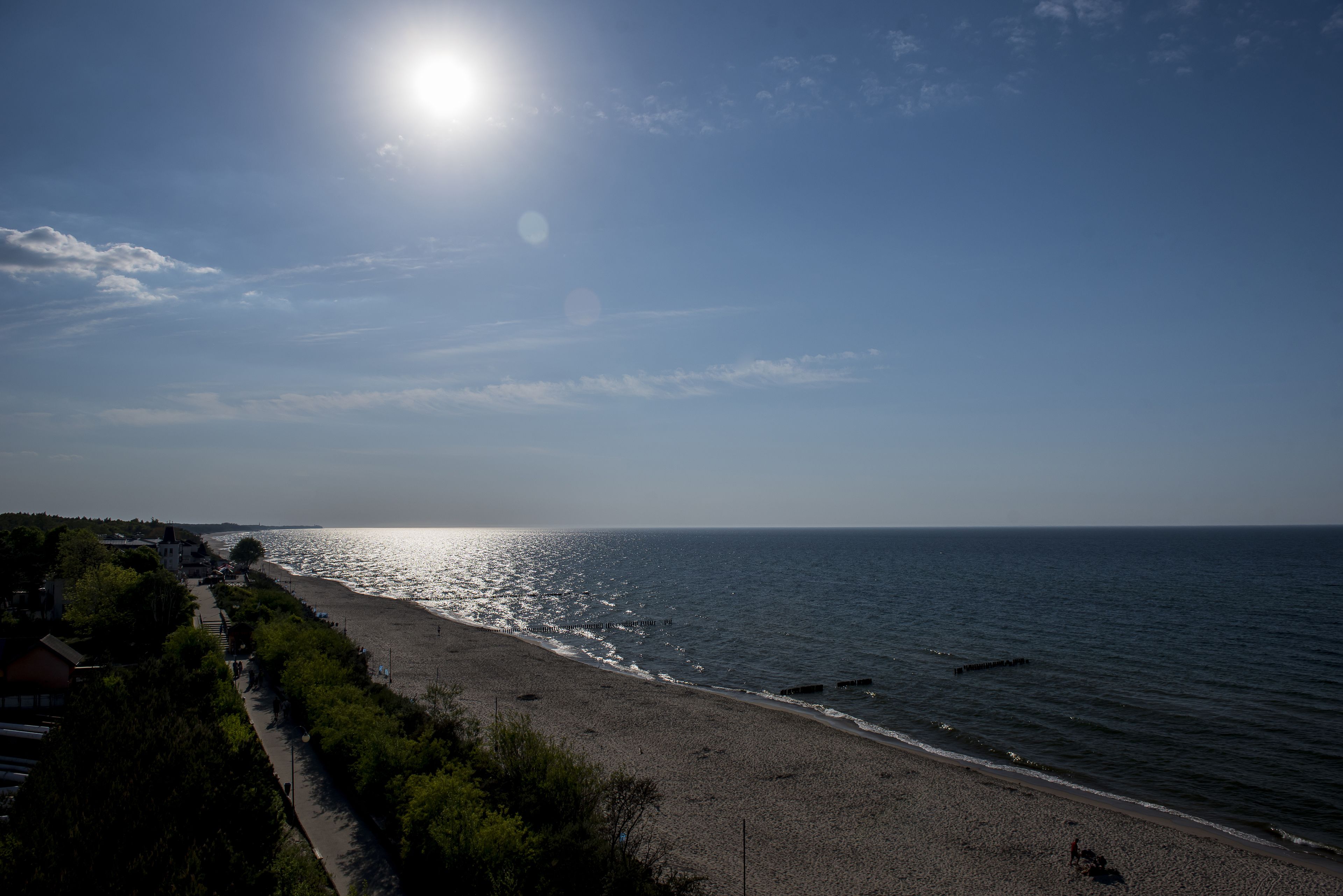 Una playa con cielo despejado, sol radiante y mar tranquilo.