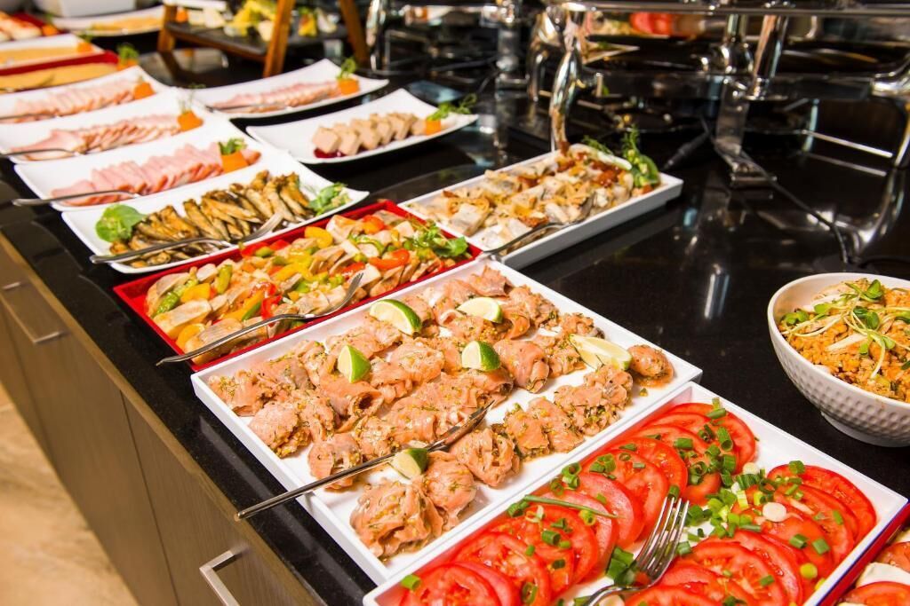 Un bufé con diversos platos, incluyendo mariscos, ensaladas y tomates en rodajas.