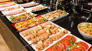 Un bufé con diversos platos, incluyendo mariscos, ensaladas y tomates en rodajas.
