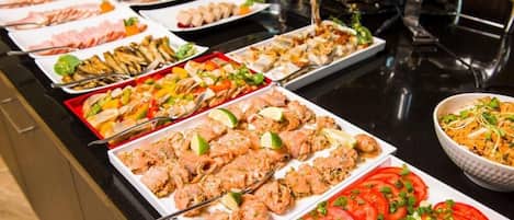 Un bufé con diversos platos, incluyendo mariscos, ensaladas y tomates en rodajas.