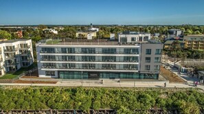 A multi-story hotel with a modern design, featuring a rooftop terrace and a landscaped courtyard. - Baltivia Sea Resort (Mielno)