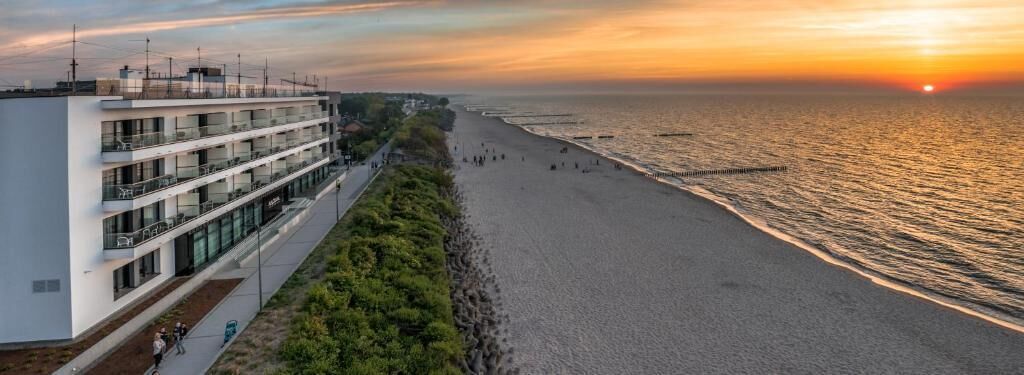 A modern hotel with multiple balconies overlooking a beach.
