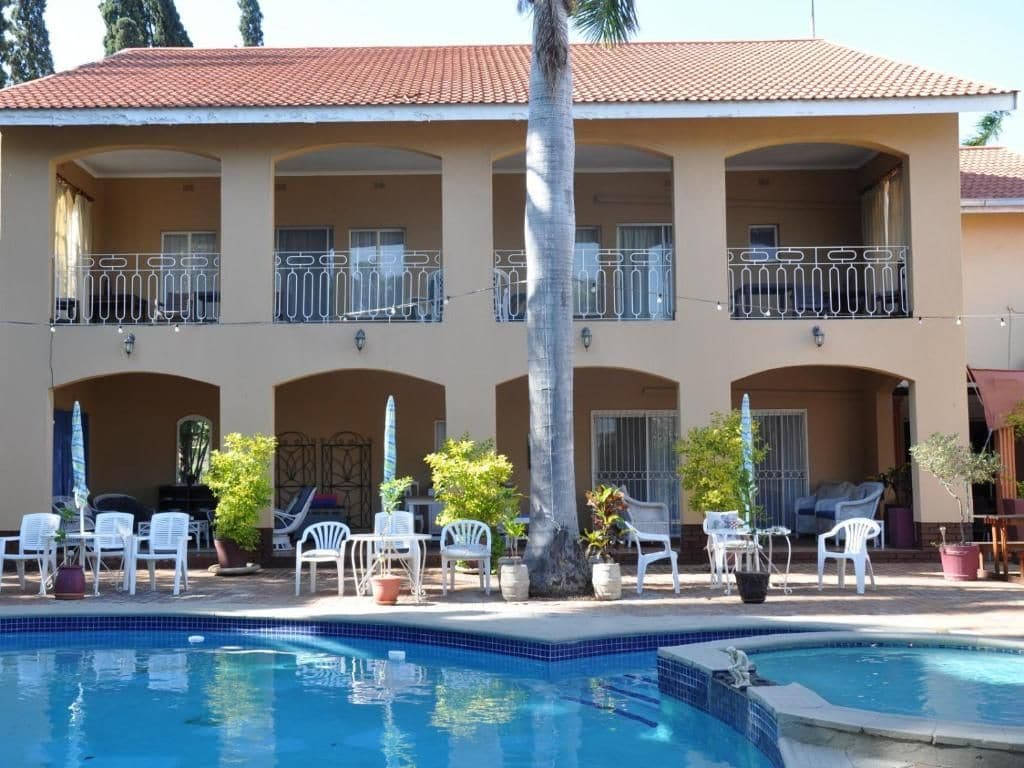 A hotel with a swimming pool, outdoor seating, and a two-story building with balconies.