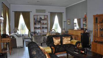 Una sala de estar con un sofá, sillones, una mesita de centro y una estantería.