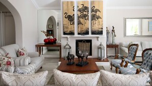 Un salon spacieux avec une cheminée, un ensemble de canapés, un fauteuil à motifs et un élément décoratif mural.