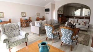 Un salon spacieux comprenant un canapé, deux fauteuils, une table basse et un coin repas avec une table et des chaises.