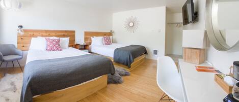 A hotel room with two beds, a desk, a chair, a TV, and a mirror.