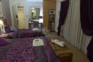 Habitació d'hotel amb dos llits, una taula de treball, una cadira, un armari i una televisió.