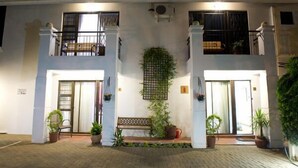 A two-story building with a balcony on the upper floor, a bench, and potted plants in the entrance area. - La Boheme Guesthouse (Bloemfontein)