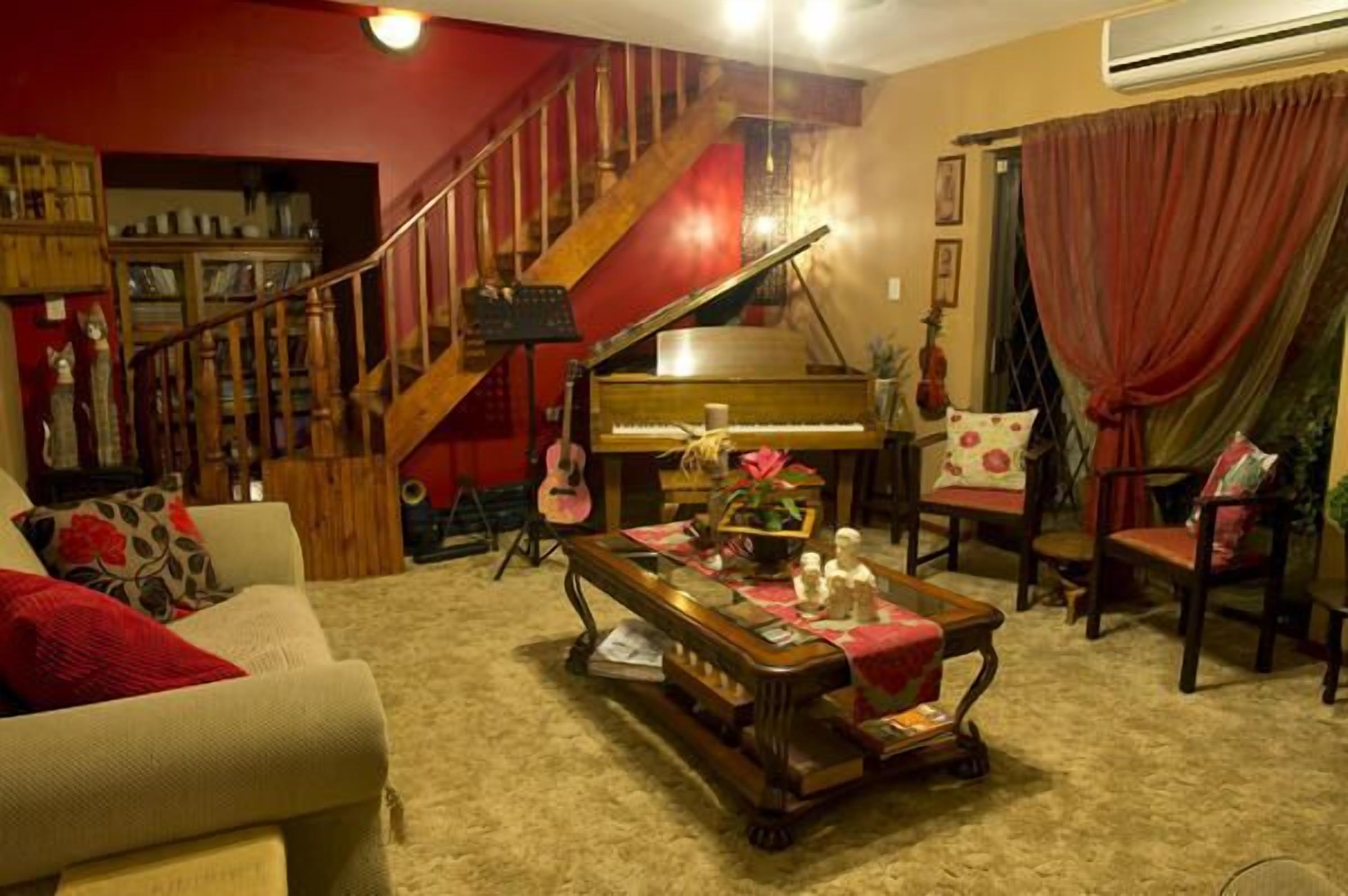 Una sala de estar con un piano de cola, una escalera y una zona de estar acogedora.