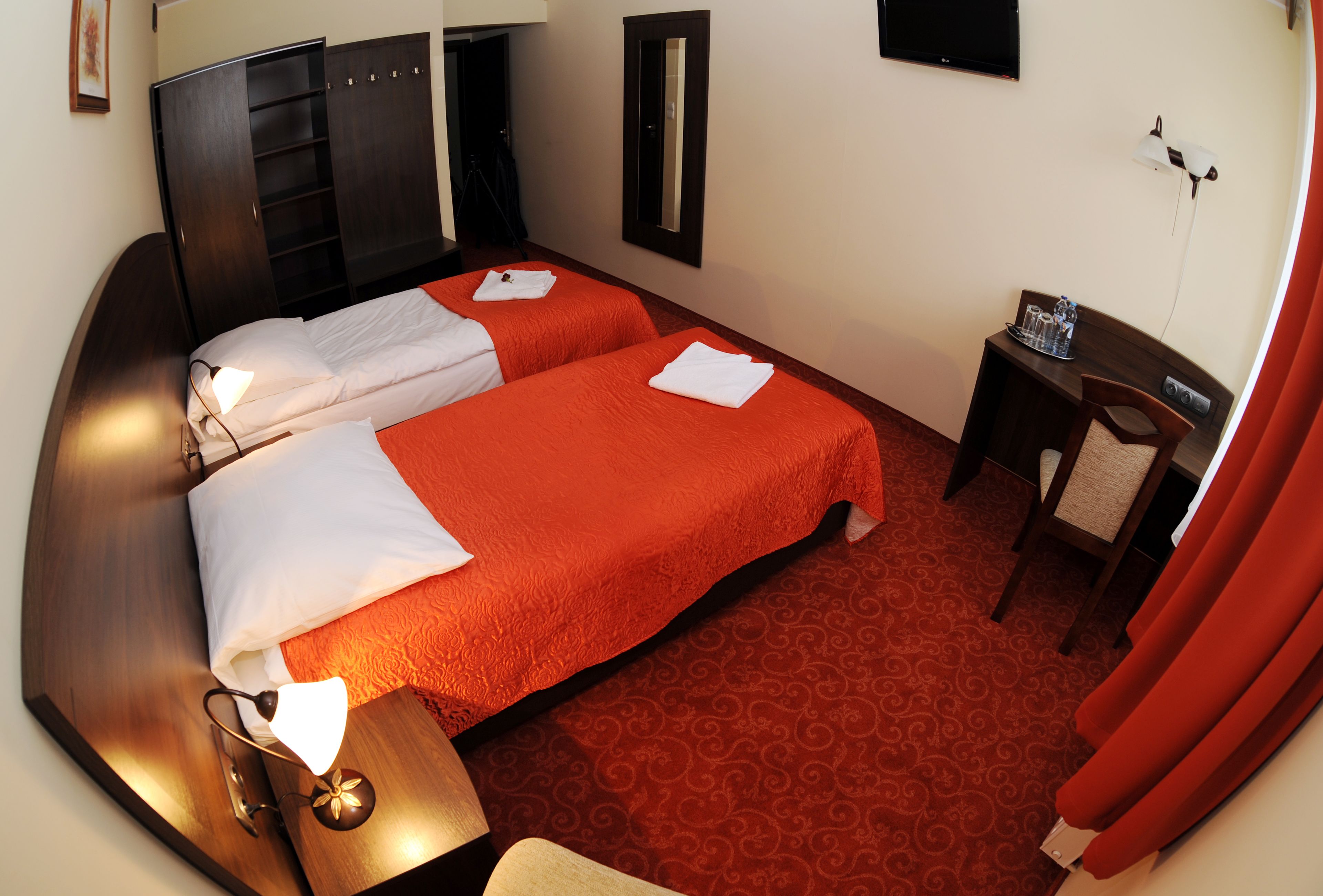 Una habitación de hotel con dos camas, un escritorio, una silla, un televisor y un armario.