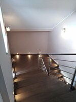Uma escada moderna com corrimãos de metal e acabamento em madeira escura.