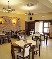 Uma sala de jantar com paredes de tijolo, várias mesas, cadeiras e lustres.