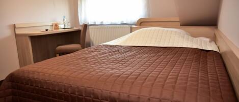 Una habitación de hotel con una cama, un escritorio y una silla.