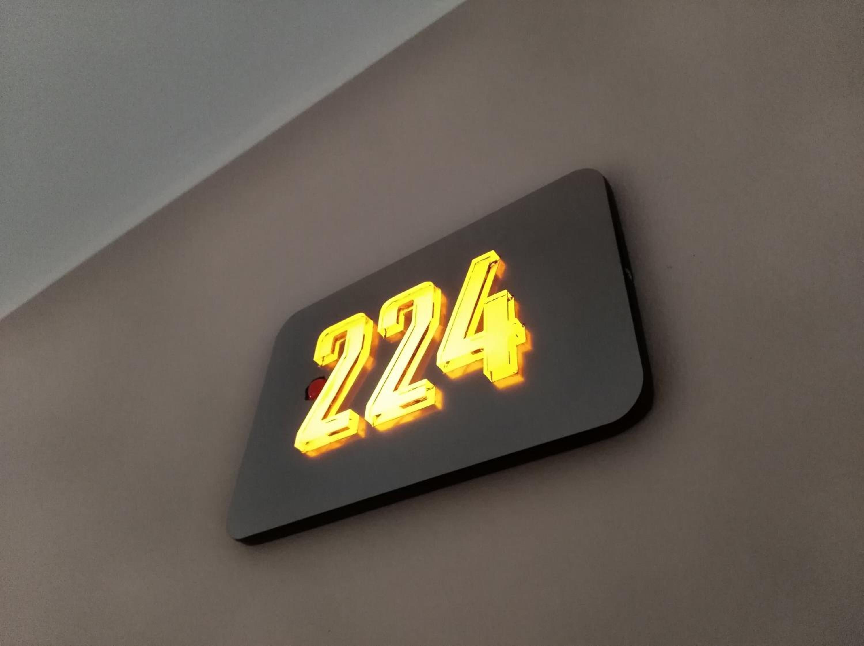 A lit-up number '224' on a wall.