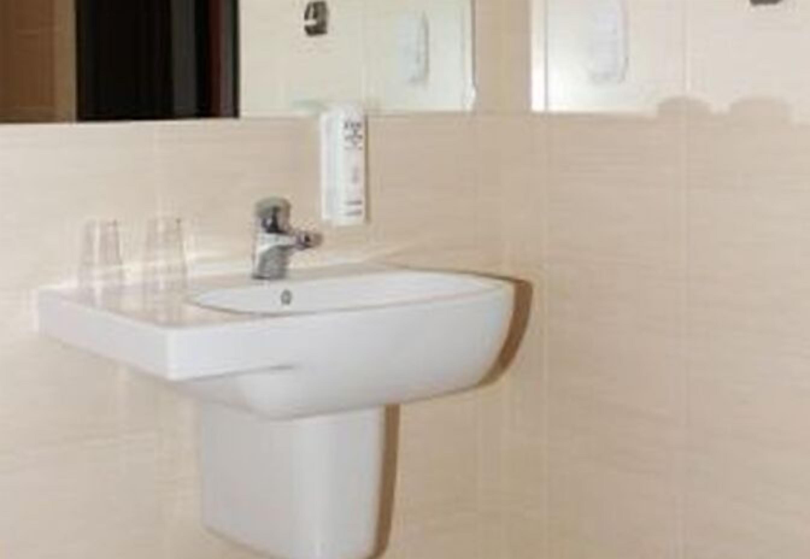 A bathroom with a white sink, a mirror, and a towel rack.