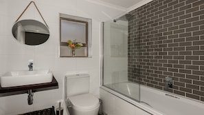 A bathroom with a white sink, toilet, and a glass-enclosed shower.