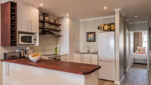 Una cocina moderna con armarios blancos, una encimera de madera y un microondas integrado.