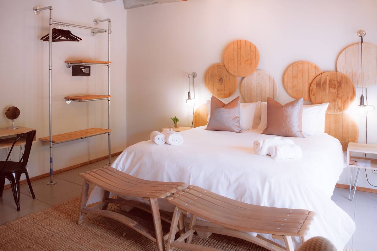 Un dormitorio ordenado con una cama grande, cabecera de madera, mesitas de noche, un escritorio y una silla.