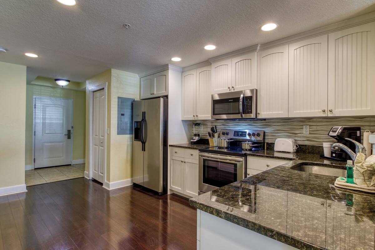 A modern kitchen with white cabinets, stainless steel appliances, and granite countertops.