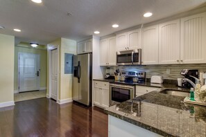 Una cocina moderna con gabinetes blancos, electrodomésticos de acero inoxidable y encimeras de granito.