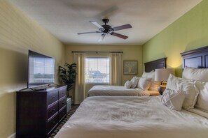 A hotel room with two beds, a ceiling fan, a TV, and a dresser. - New Hotel Collection Harbourside Resort (Indian Rocks Beach)
