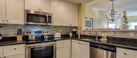Una cocina moderna con armarios blancos, electrodomésticos de acero inoxidable y encimera de granito.