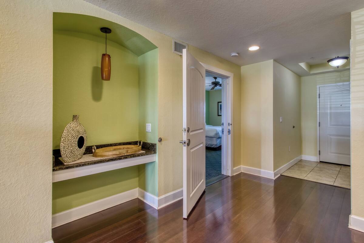 A hallway with a wooden floor, a white door, and a ceiling fan.