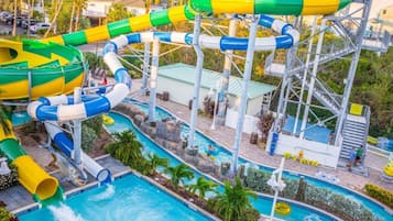 Ein Wasserpark mit mehreren Wasserrutschen und Pools, umgeben von Palmen und einem Poolbereich.