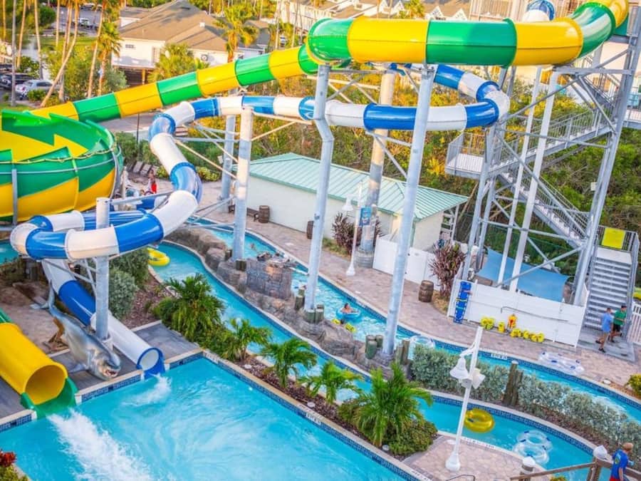 Ein Wasserpark mit mehreren Wasserrutschen und Pools, umgeben von Palmen und einem Poolbereich.