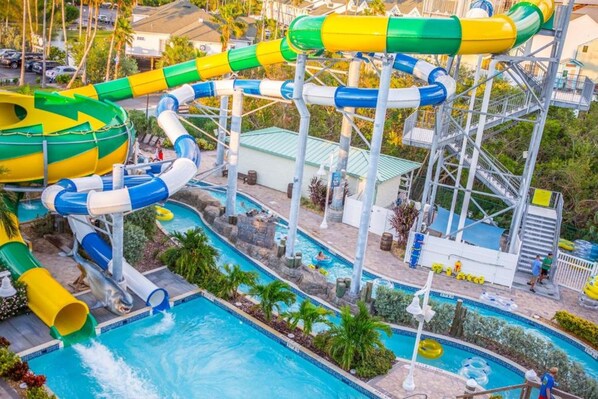 A water park with multiple slides and pools, surrounded by palm trees and a poolside area. - New Hotel Collection Harbourside Resort (Indian Rocks Beach)