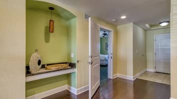 A hallway with a wooden floor, a white door, and a ceiling fan.