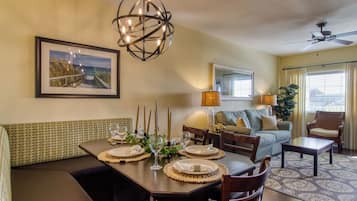 A dining area with a table set for four, a sofa, and a chair.