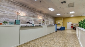 A reception area with a tiled floor, a reception desk, a blue chair, and a yellow wall.