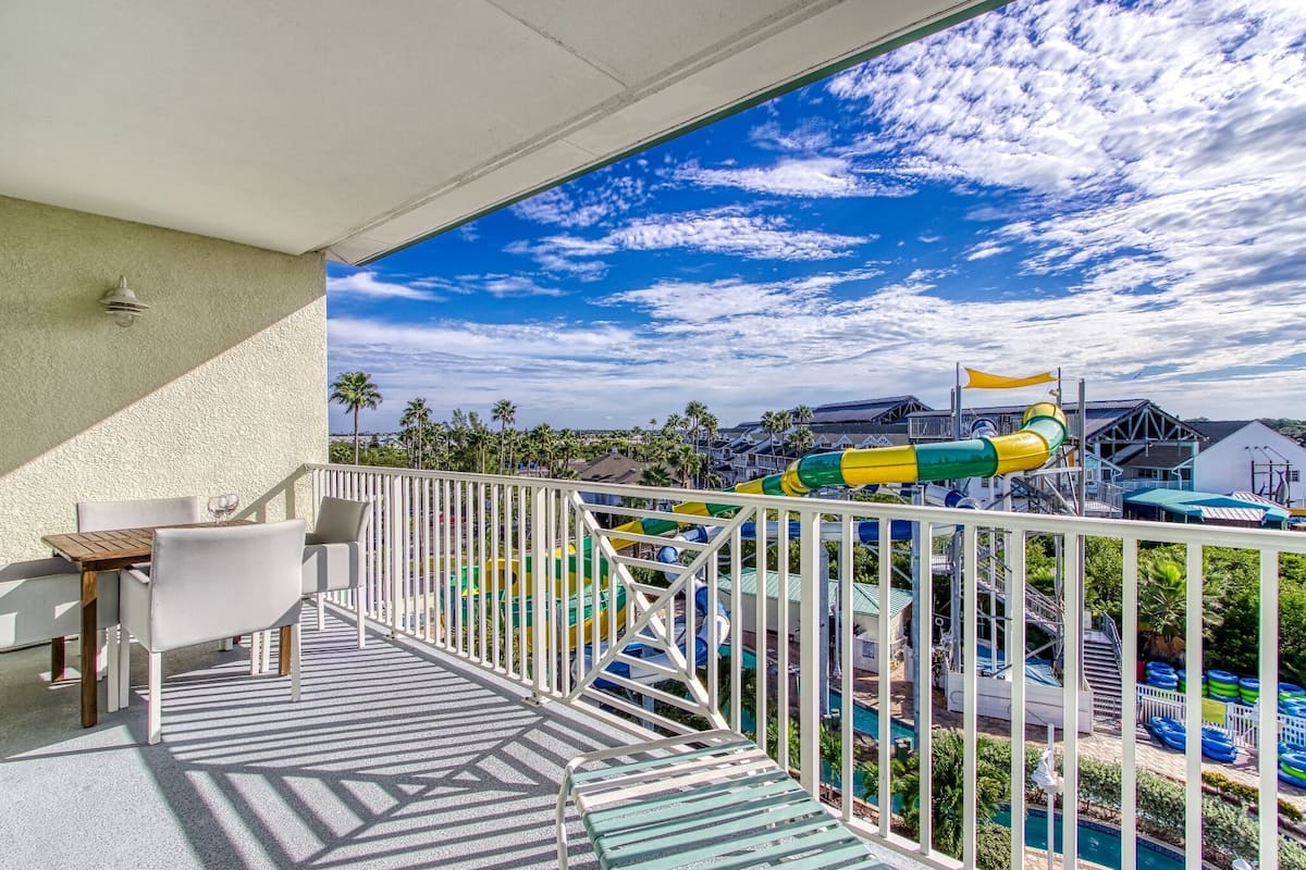 A balcony with a view of a water park, including a water slide and pool area.