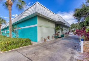 A building with a blue and white exterior, a parking lot, and surrounding greenery. - New Hotel Collection Harbourside Resort (Indian Rocks Beach)