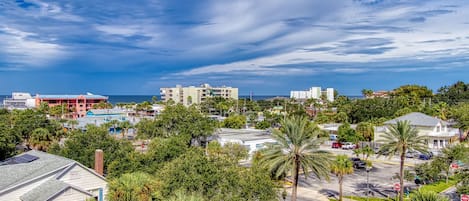 A coastal urban area with buildings, palm trees, and a clear sky.