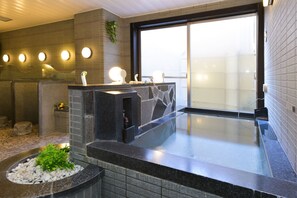 Un baño moderno con un lavamanos de piedra, un jacuzzi integrado y un ventanal amplio.