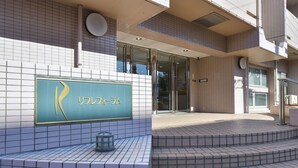 A building entrance with a sign reading "R" and a tiled wall. - Refre Forum (Tokyo)