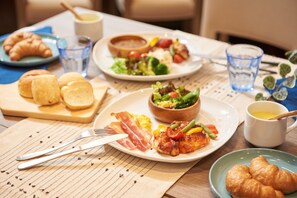 A breakfast setting with plates of food, including eggs, bacon, and vegetables, along with croissants and coffee. - Keio Presso Inn Kudanshita (Tokyo)