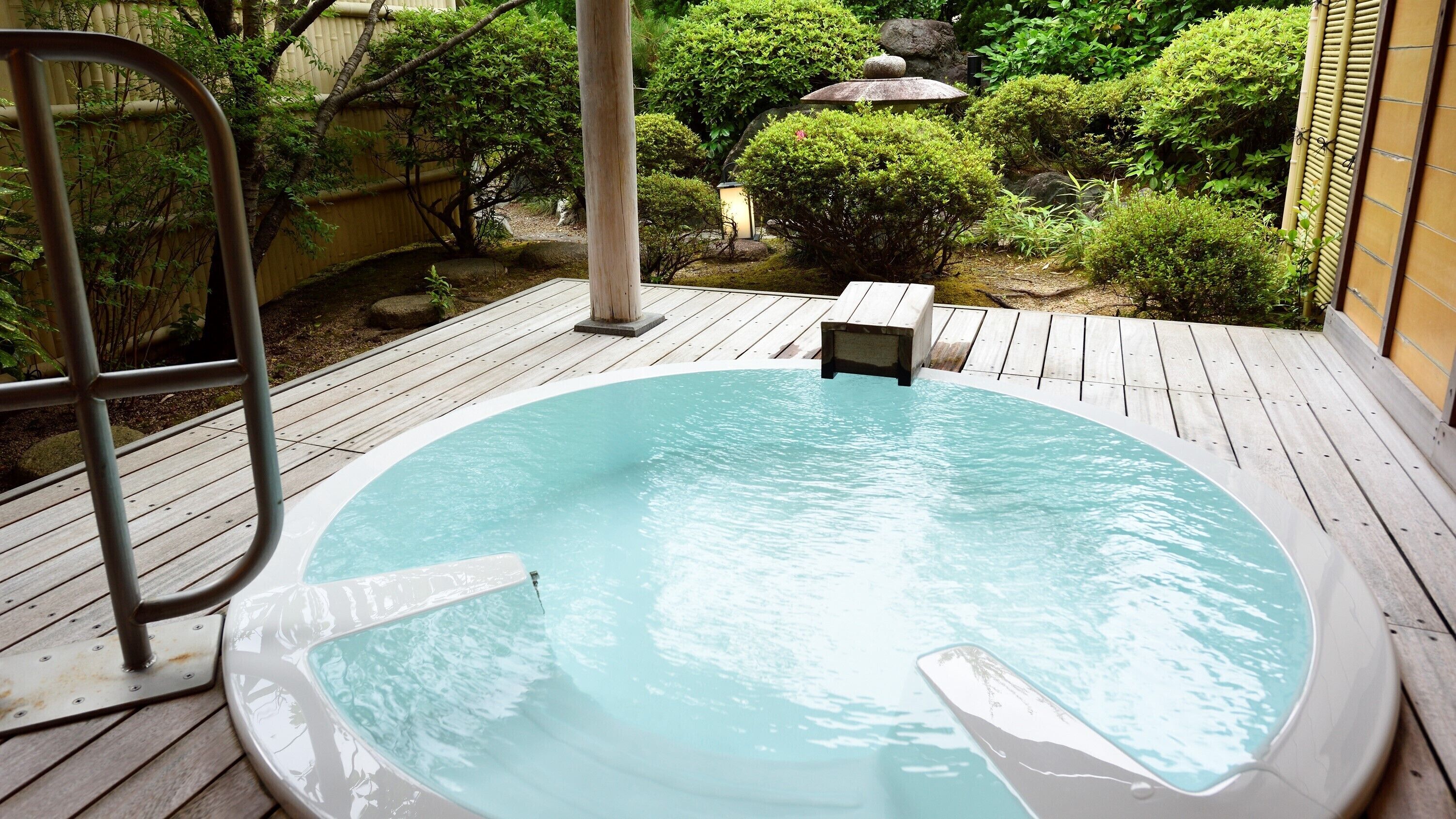 Un jacuzzi en una terraza de madera rodeado de follaje.